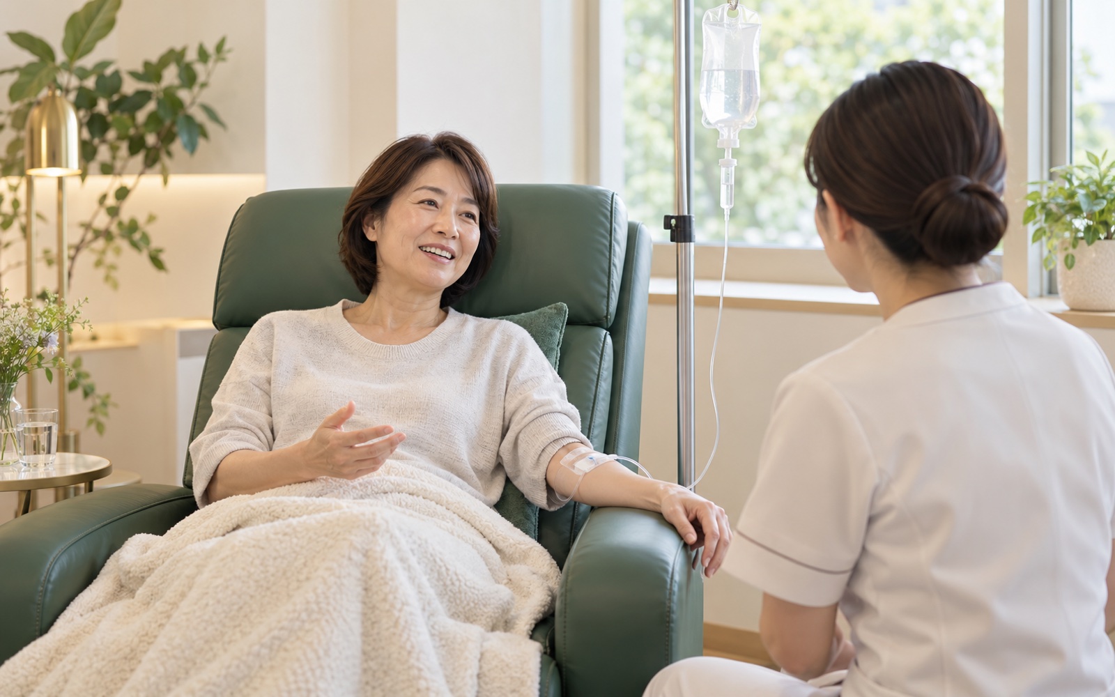 リクライニングチェアで点滴を受けながら、看護師と話す患者
